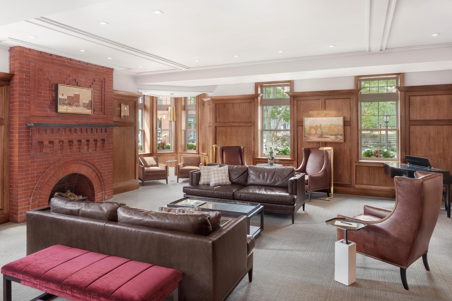 Spacious lounge with leather sofas, brick fireplace, and large windows.