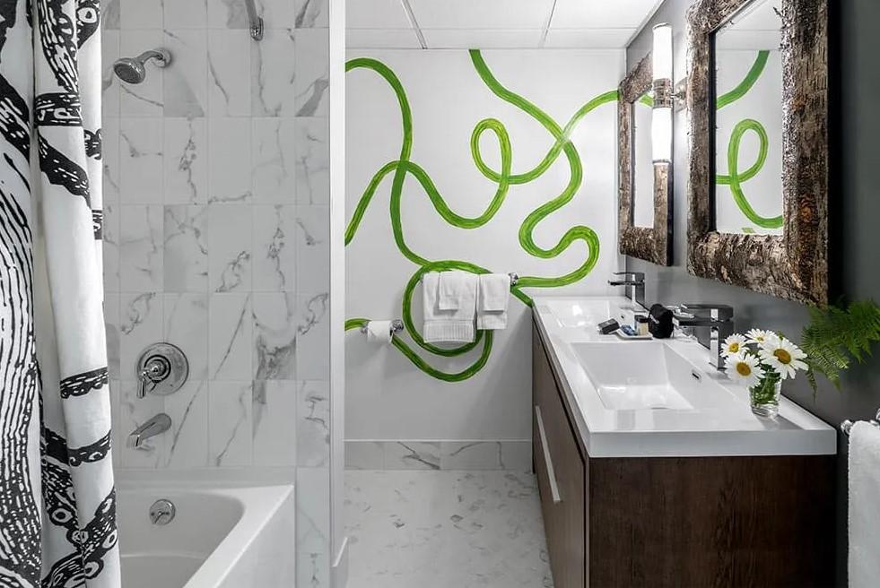 Bathroom with green swirl mural, marble accents, dark wood vanity, and decorative mirrors.