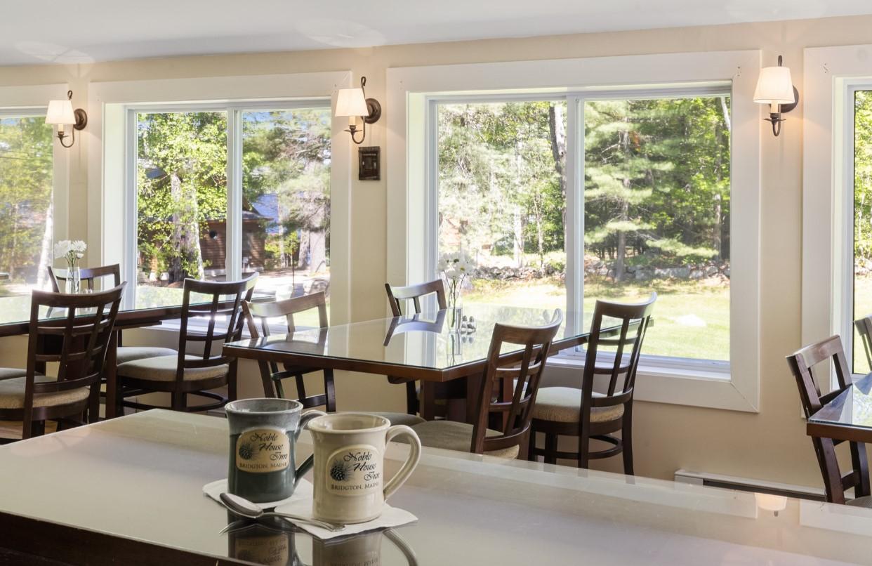 Cozy cafe with large windows, wooden tables, and two mugs on the counter.