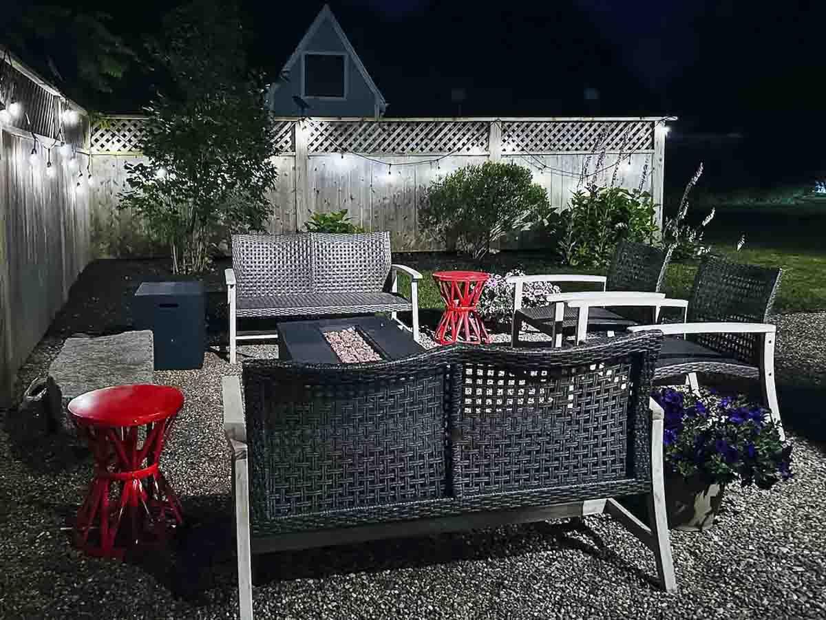 Patio furniture set with lights at night, featuring red and grey pieces.