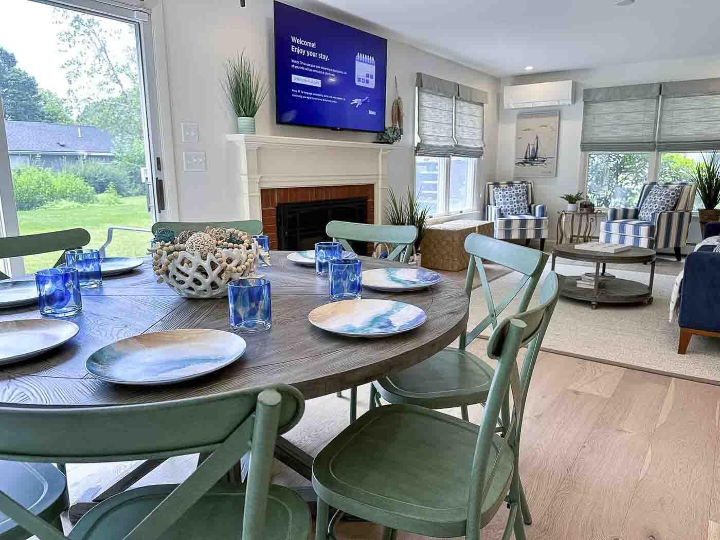 Dining room with green chairs, set table, and a view of a living room and garden.