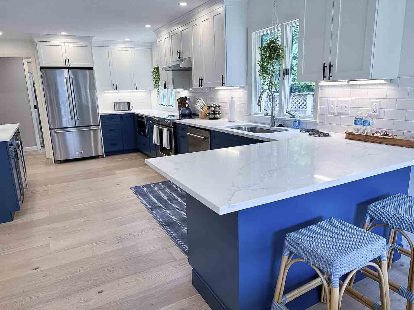 Modern kitchen with blue cabinets, white countertops, and stainless steel appliances.