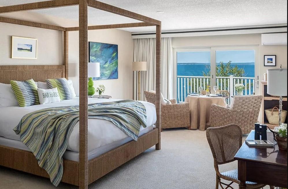 Spacious bedroom with a canopy bed, ocean view, and cozy seating area.