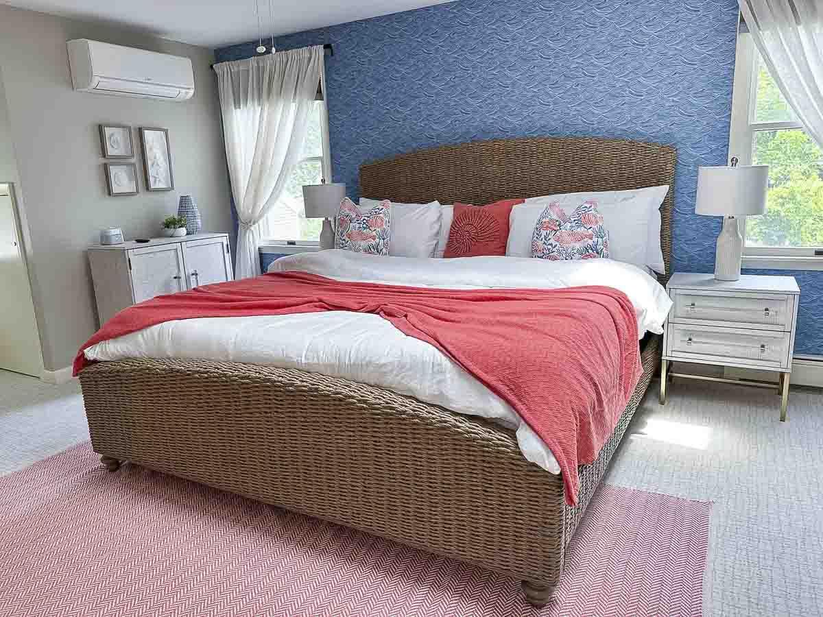 Cozy bedroom with a wicker bed, coral blanket, and blue accent wall.