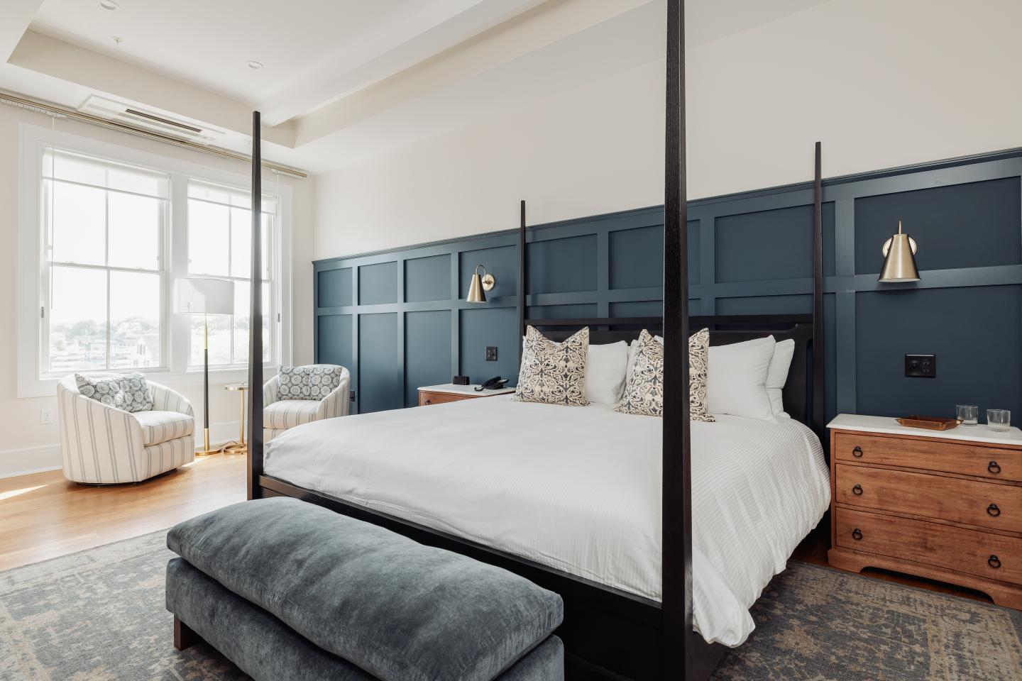 Four-poster bed in a spacious, elegant bedroom with natural light.