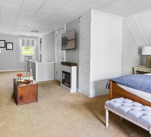 Cozy bedroom with a fireplace, white walls, and a blue bedspread.