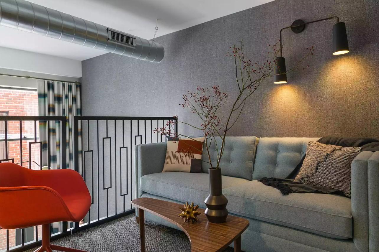 Cozy living room with gray sofa, red chair, and wall lights.