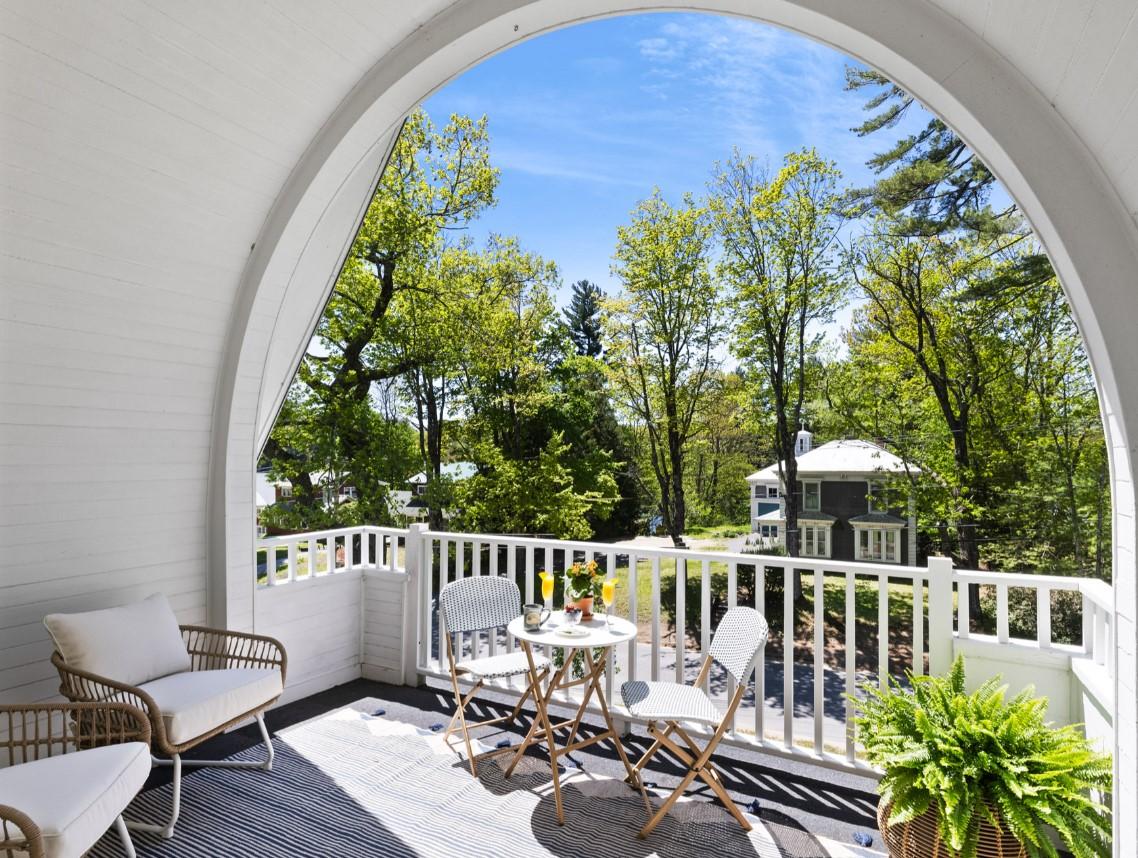 Arched porch with chairs, table, and lush trees in view.