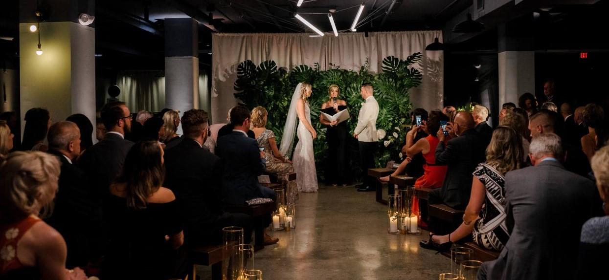 Wedding ceremony in a dimly lit venue with seated guests.