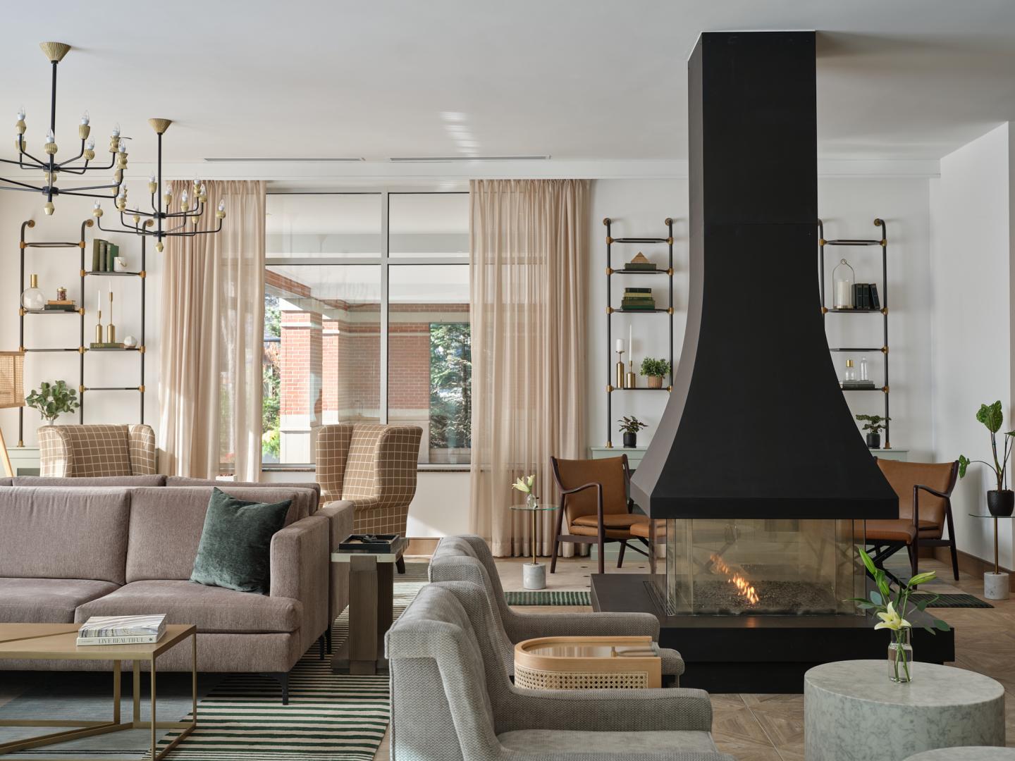 Modern living room with fireplace, grey sofas, and a chandelier.