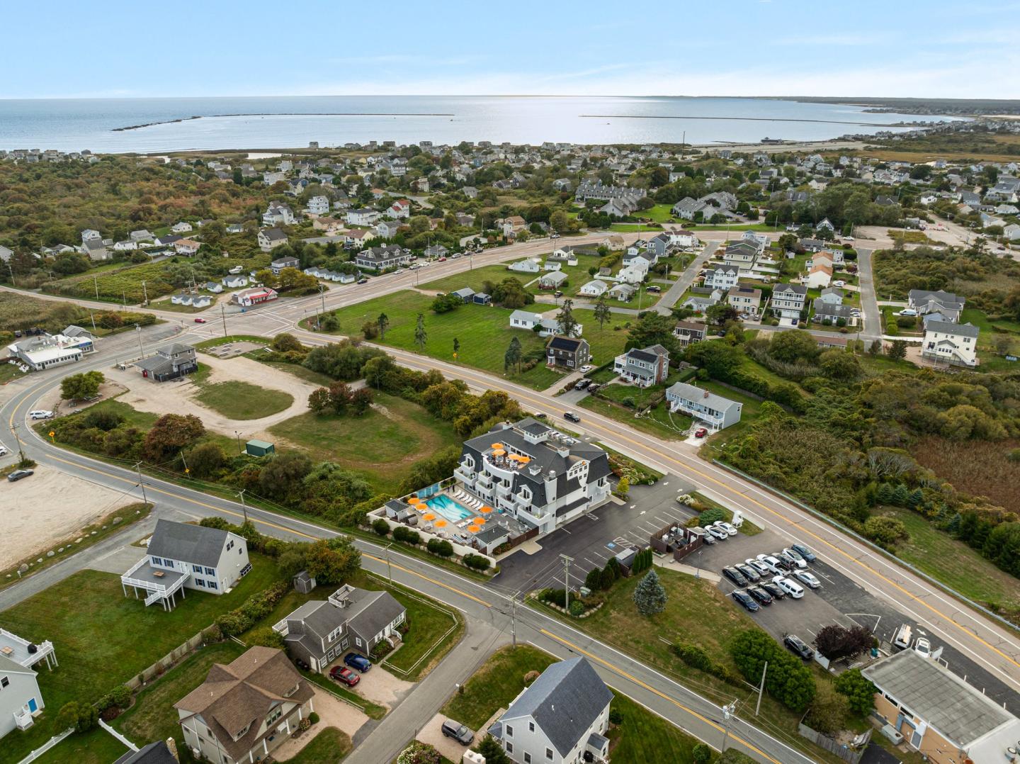 Aerial view of a coastal town with boutique hotel & outdoor pool in the center.