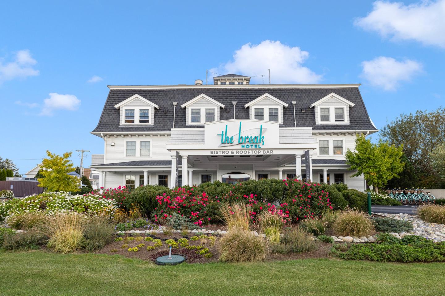 Exterier of boutique hotel with a manicured garden, blue sky, and fluffy clouds.