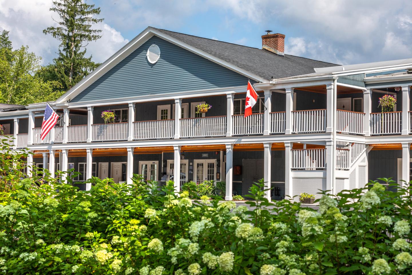 Shire Woodstock building with American and Canadian flags, surrounded by greenery.