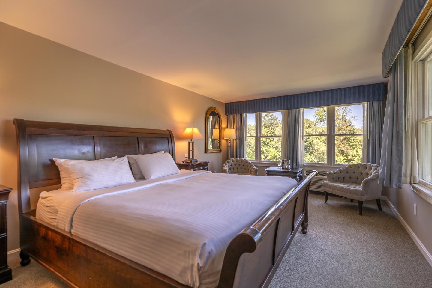 Cozy bedroom with king-size bed, large window view, and soft lighting.