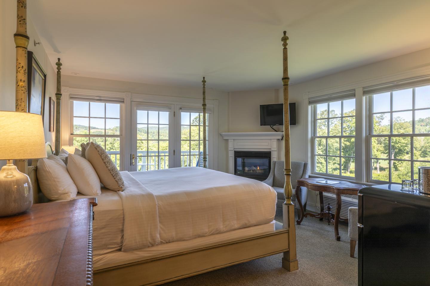 Cozy bedroom with large bed, windows, and a fireplace.