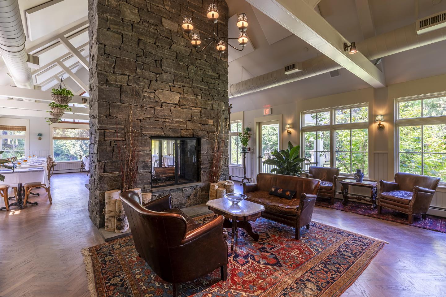 Cozy lounge with leather chairs, stone fireplace, and large windows.