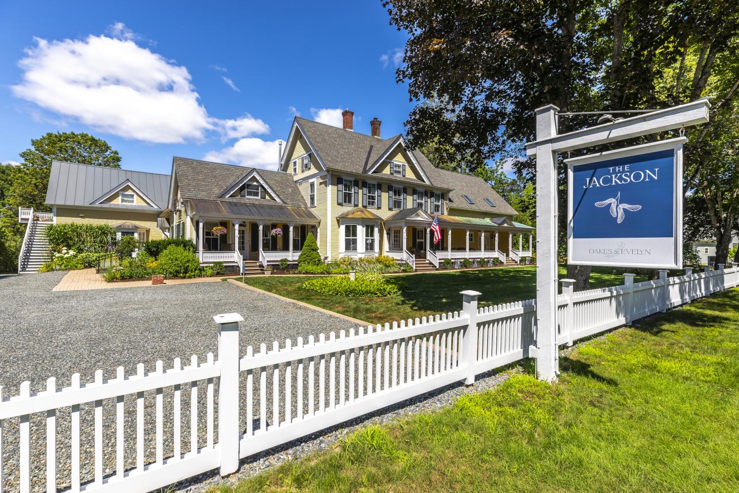Large inn with a white picket fence and blue sky.