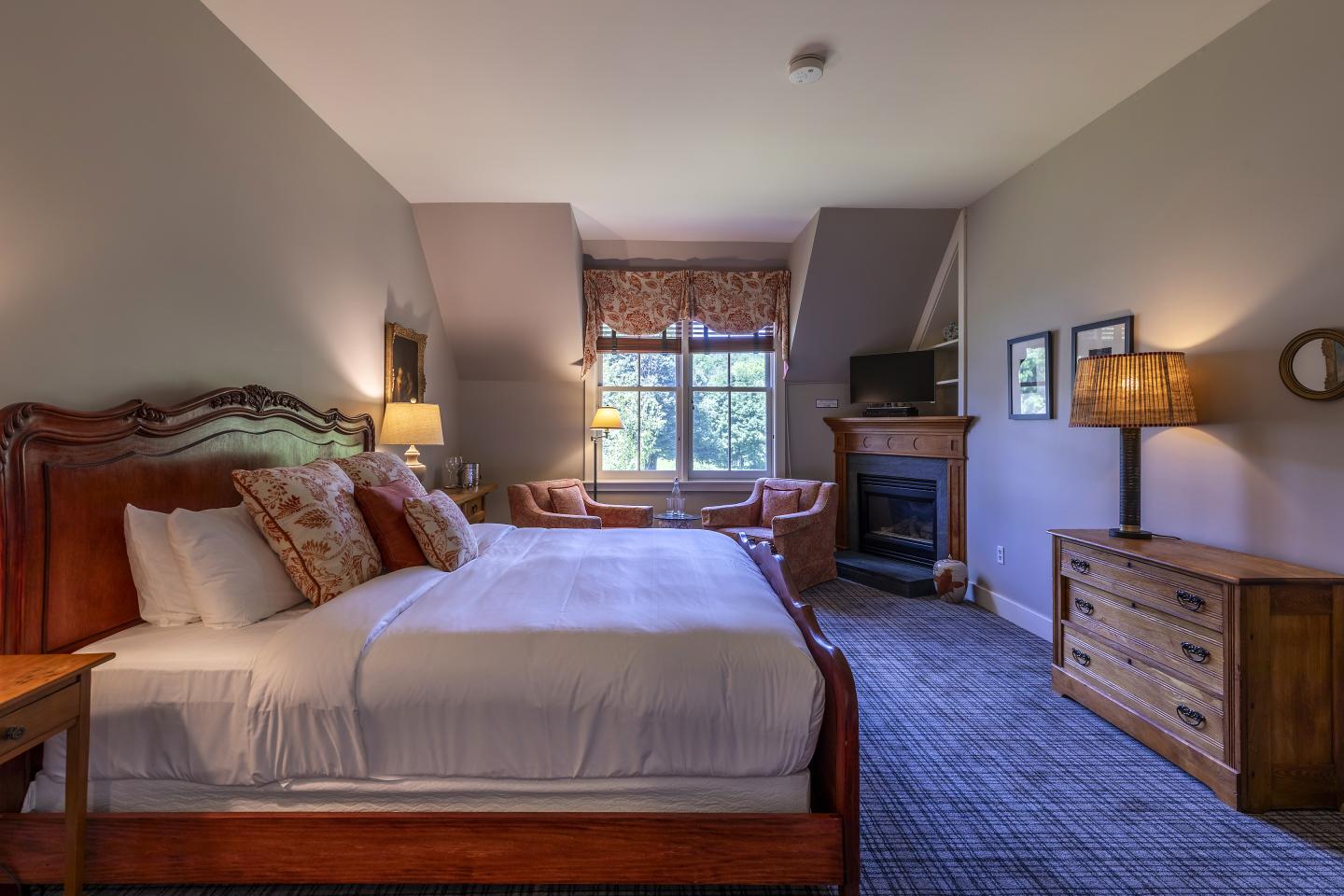 Cozy bedroom with a large bed, fireplace, and window view.