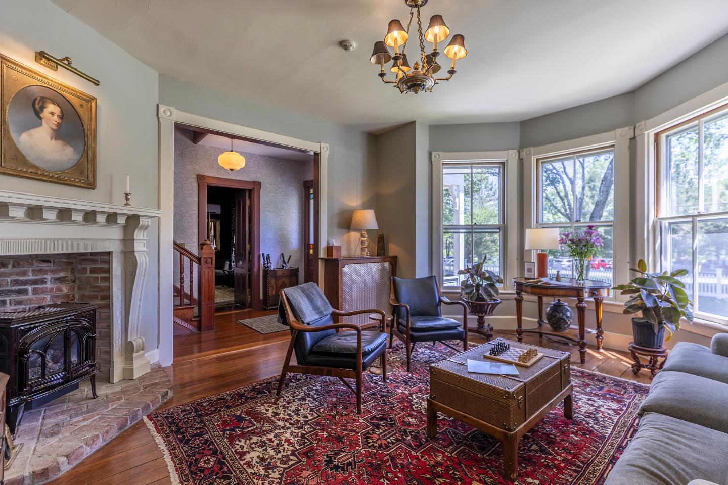 Cozy living room with vintage decor, large windows, and a chandelier.