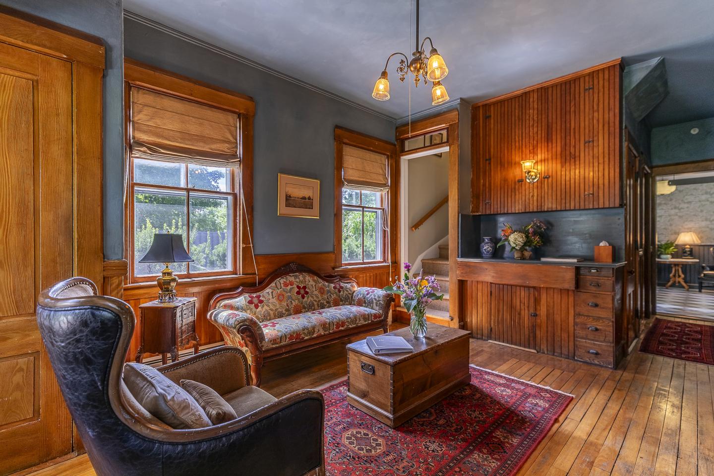 Cozy vintage living room with wooden paneling, floral sofa, and warm lighting.