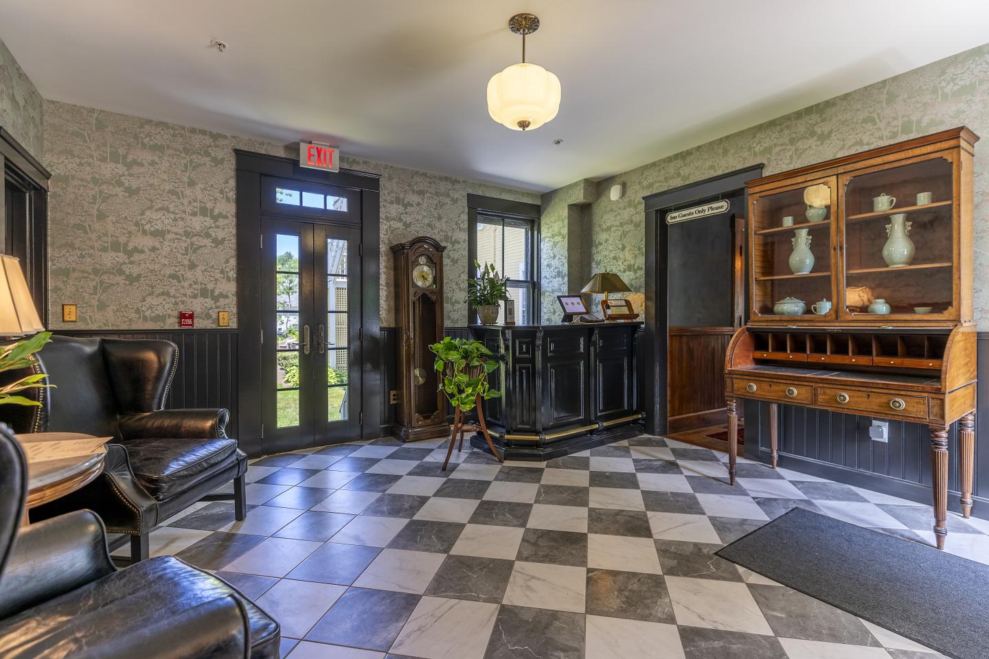 Lobby with checkered floor, vintage furniture, and a grandfather clock.