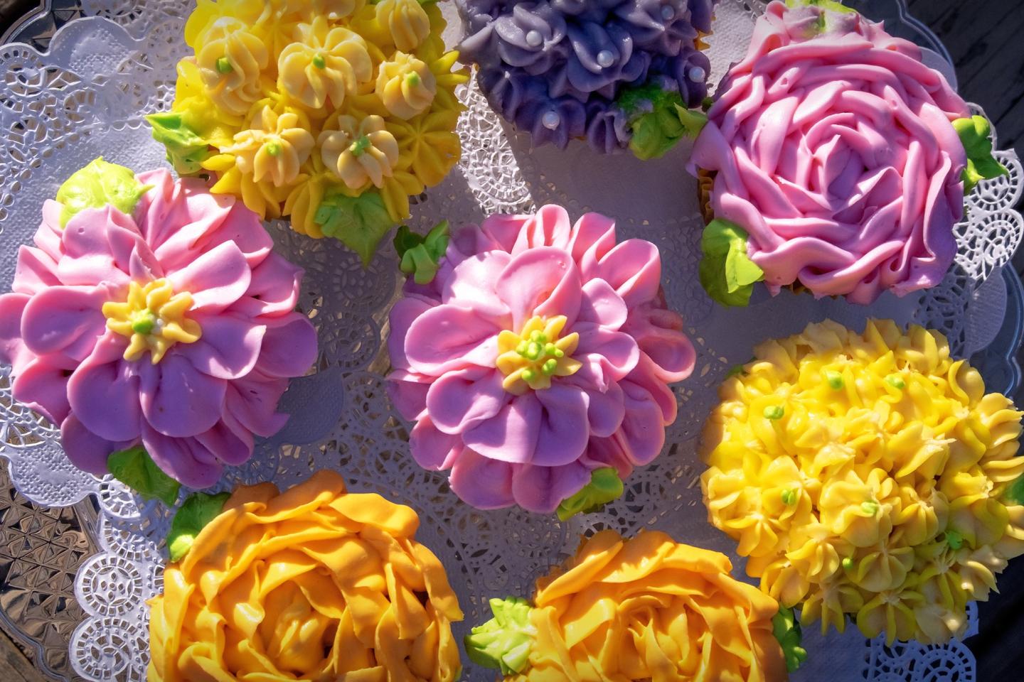 Colorful flower-decorated cupcakes on a lacy doily.