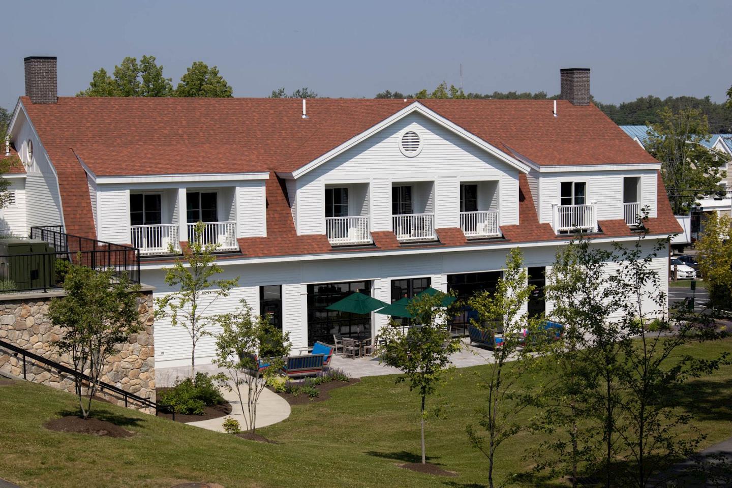 Two-story building with a red roof and green lawn.