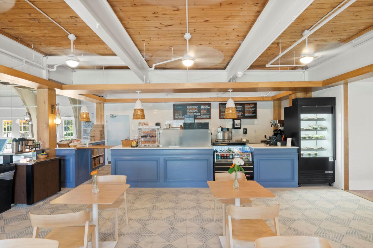 Cozy cafe interior with wooden ceiling, blue counter, and seating area.