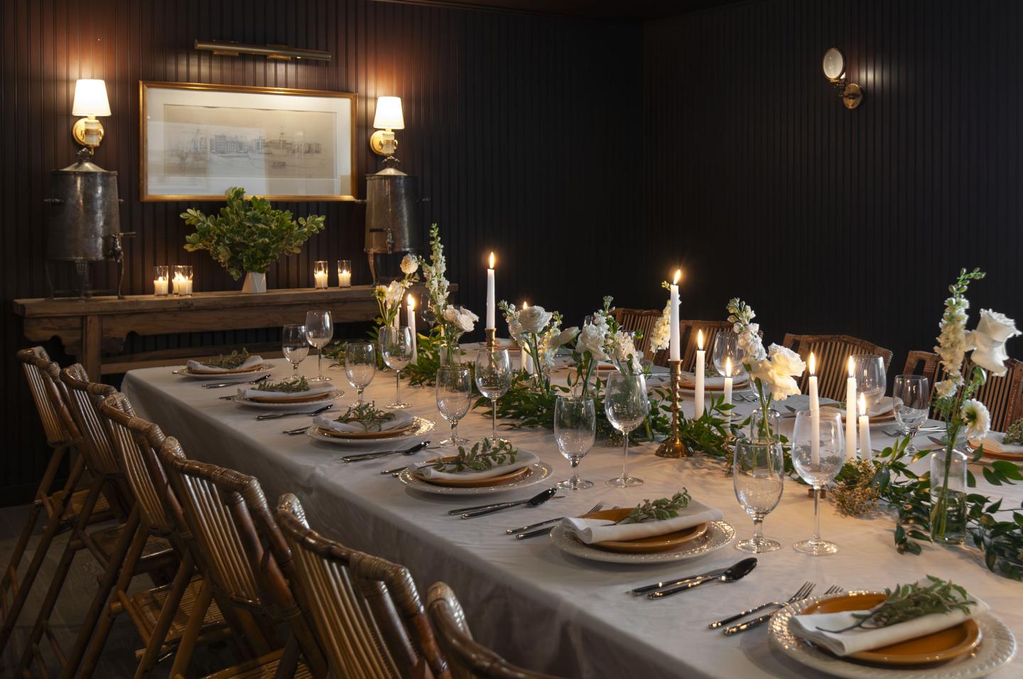 Elegant dining table set for dinner with candles and greenery.