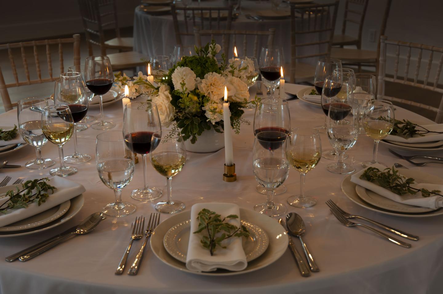 Elegant table setting with wine glasses, candles, and floral centerpiece.