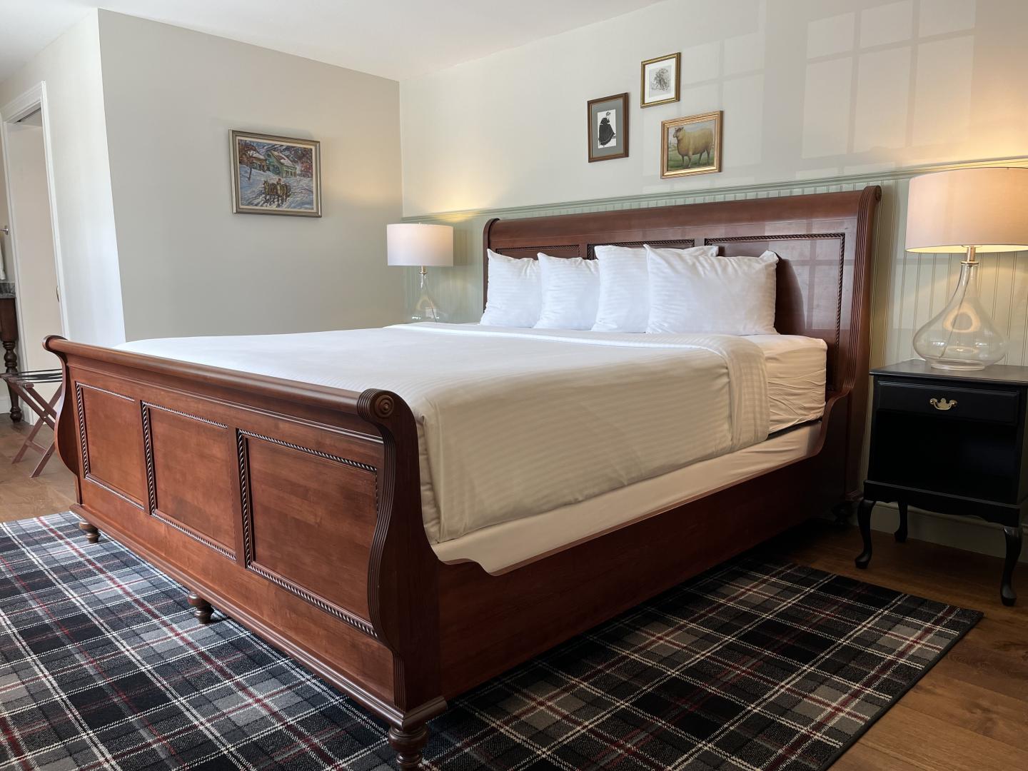 Spacious bedroom with a wooden bed, white bedding, and bedside lamps.