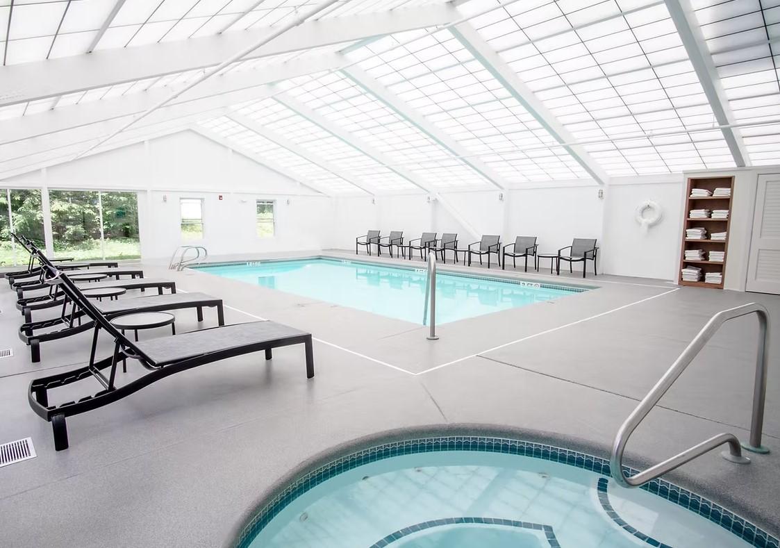 Indoor pool area with lounge chairs and skylights.