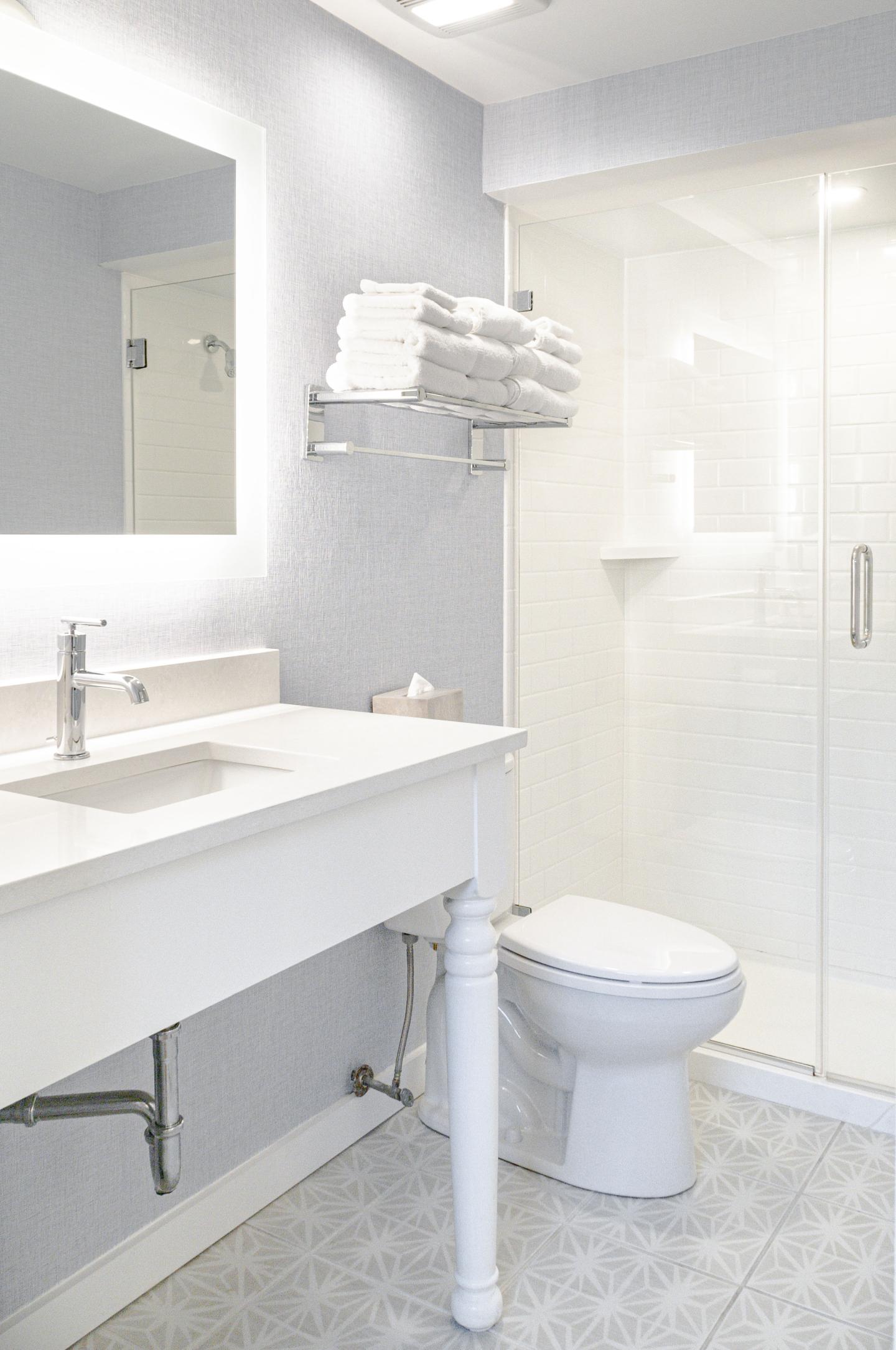 Modern white bathroom with sink, toilet, and glass shower.