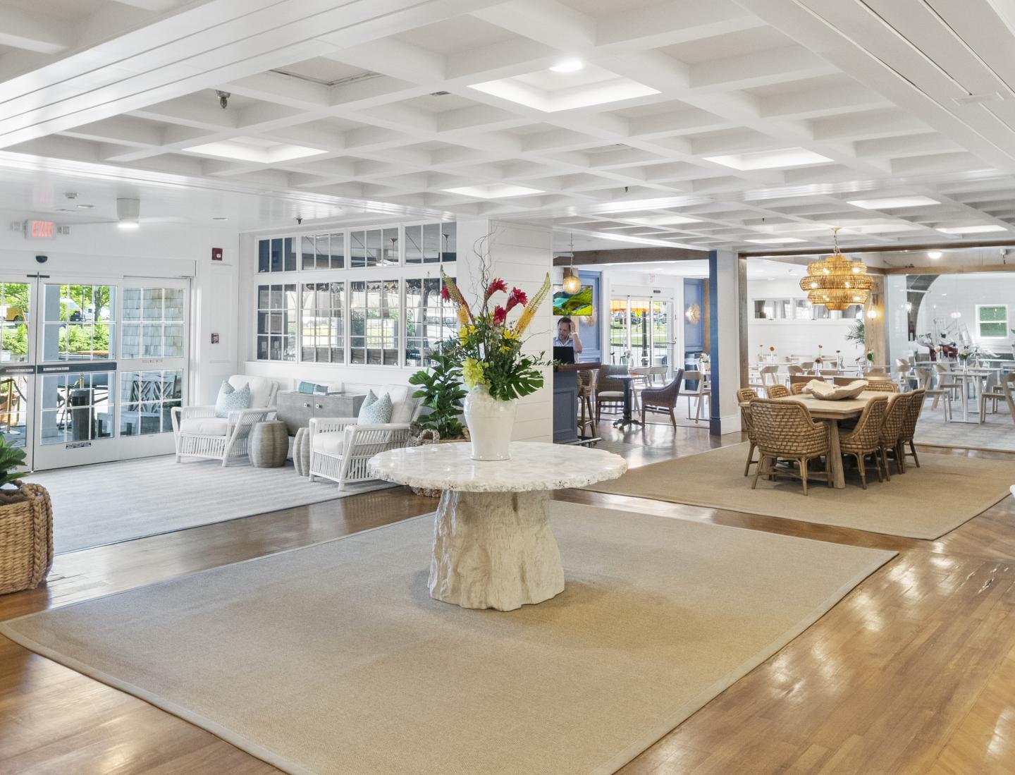 Bright, spacious lobby with a central table, flowers, seating areas, and large windows.