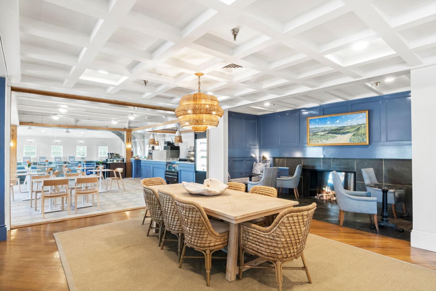 Dining area with wicker chairs, wooden table, blue accent walls, and pendant lights.