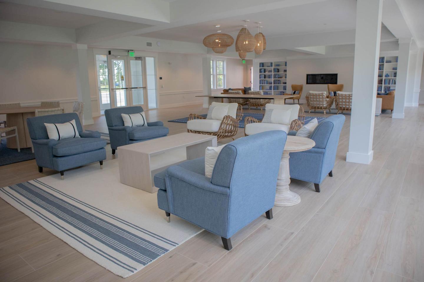 Spacious living room with blue chairs, white sofas, and a striped rug.