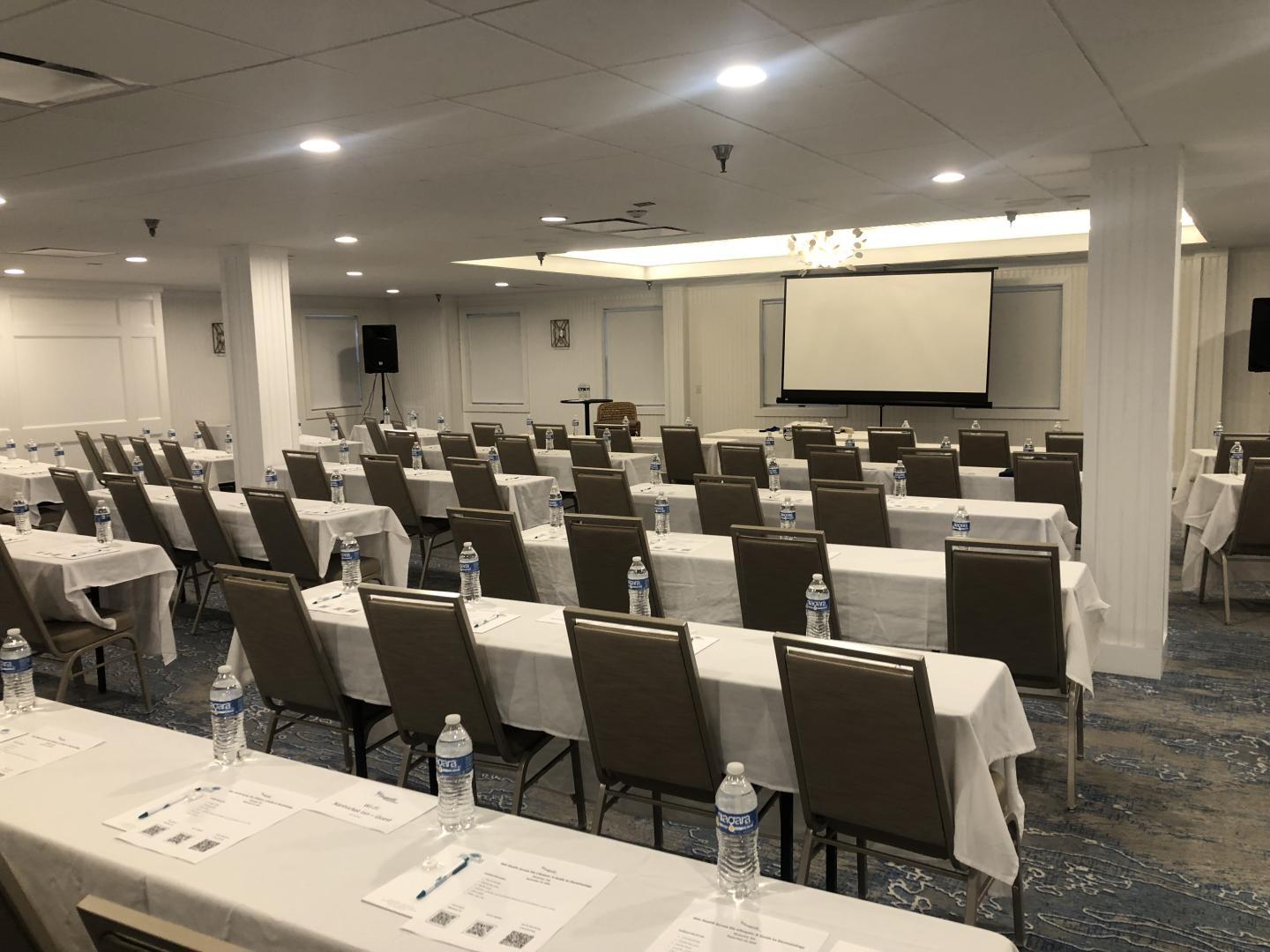 Conference room with rows of tables, chairs, and water bottles.