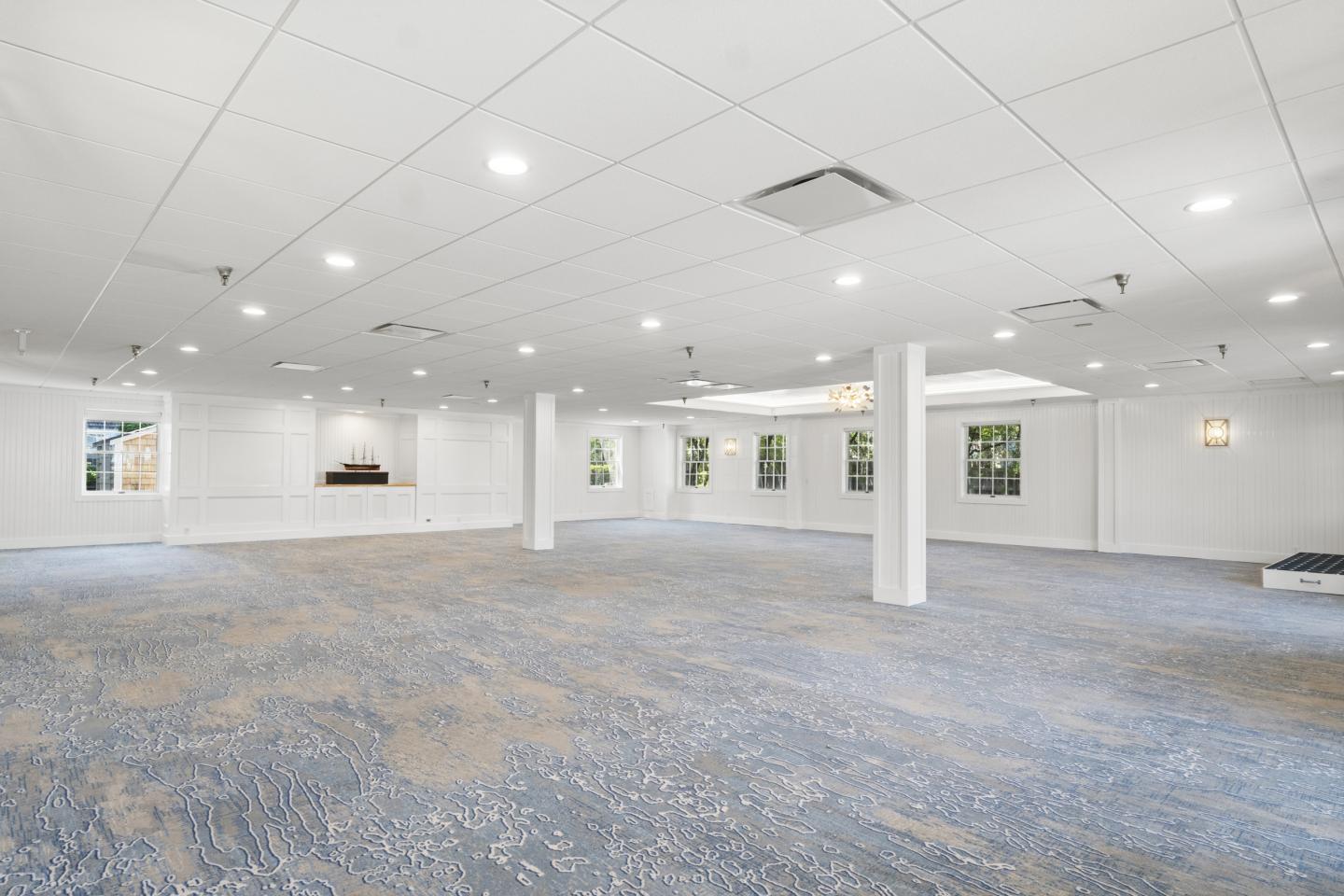 Spacious white room with blue carpet and bright lighting.