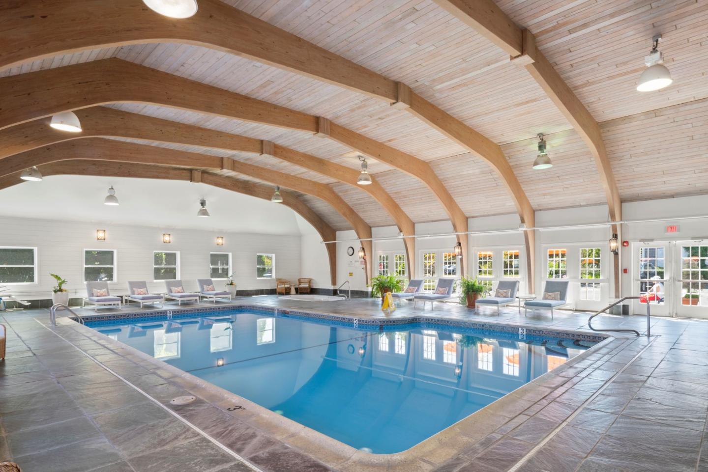 Indoor pool with wood beam ceiling, surrounded by lounge chairs.