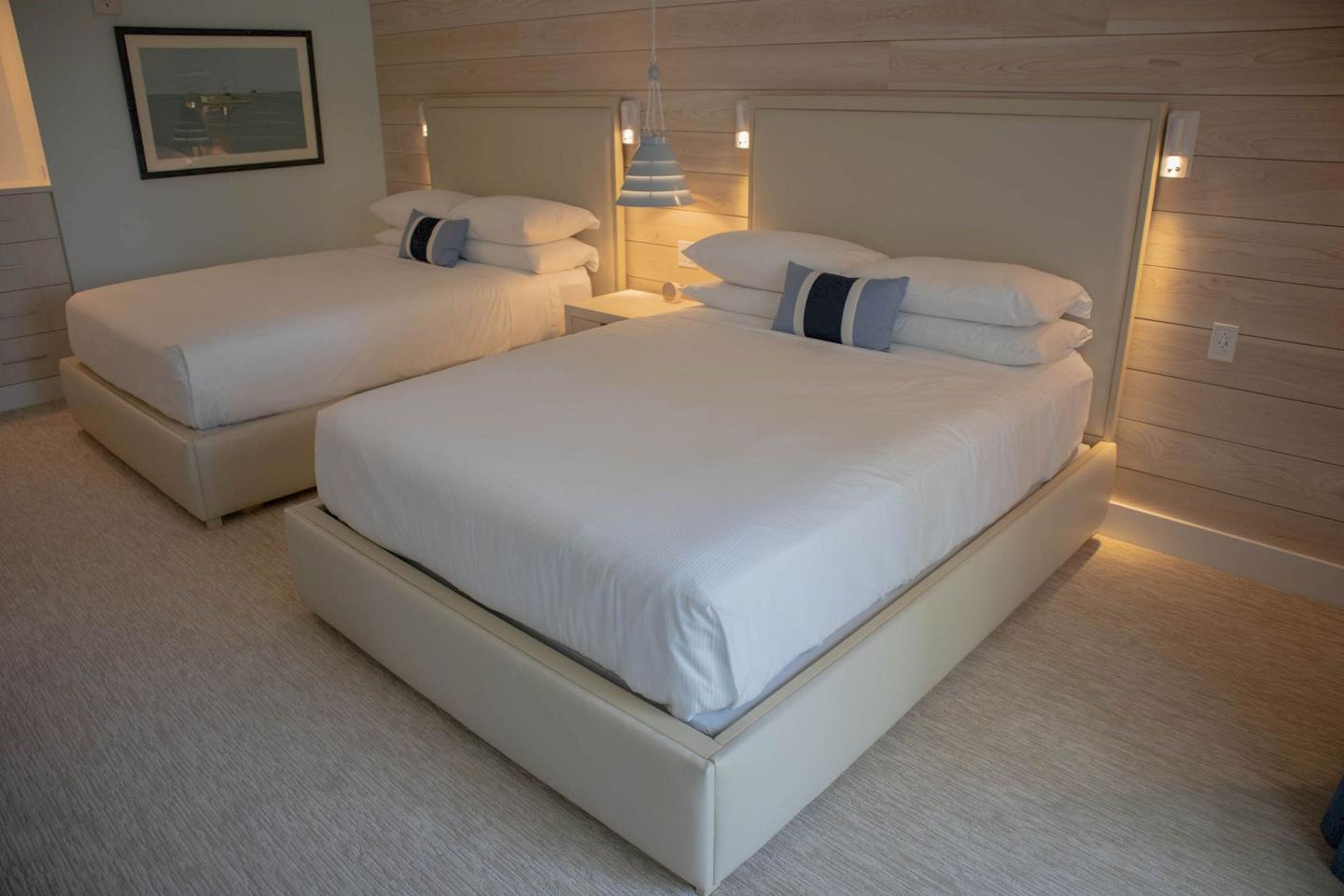 Two neatly made beds in a modern, softly lit bedroom.