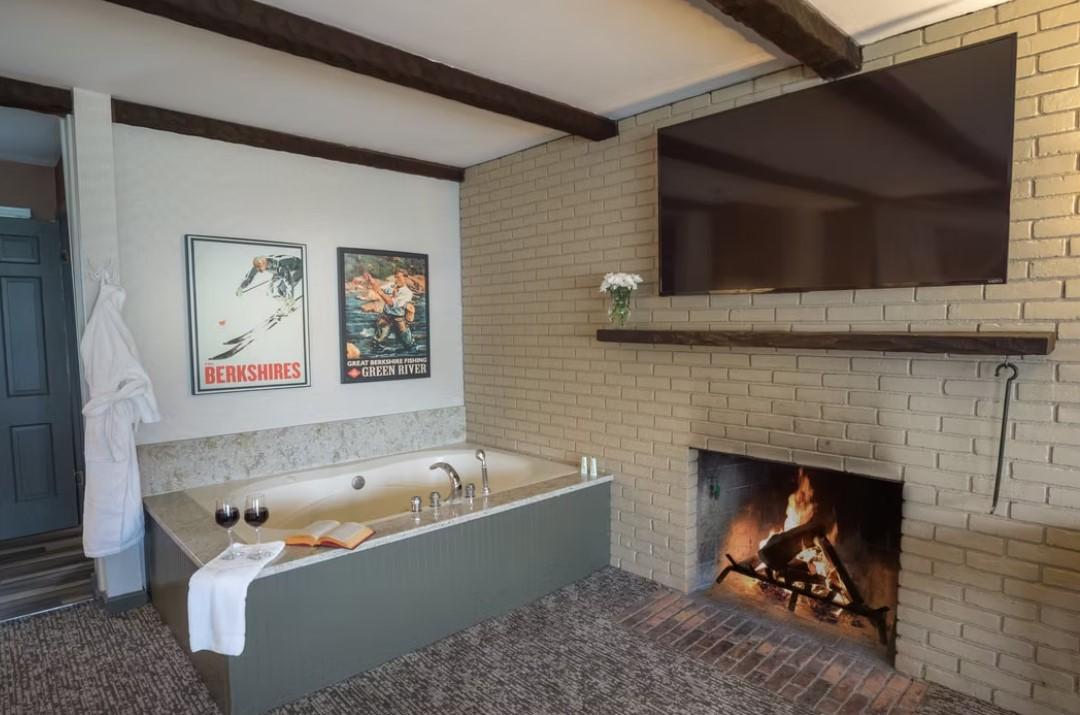 Cozy room with a tub, fireplace, and TV. Two posters on the wall.