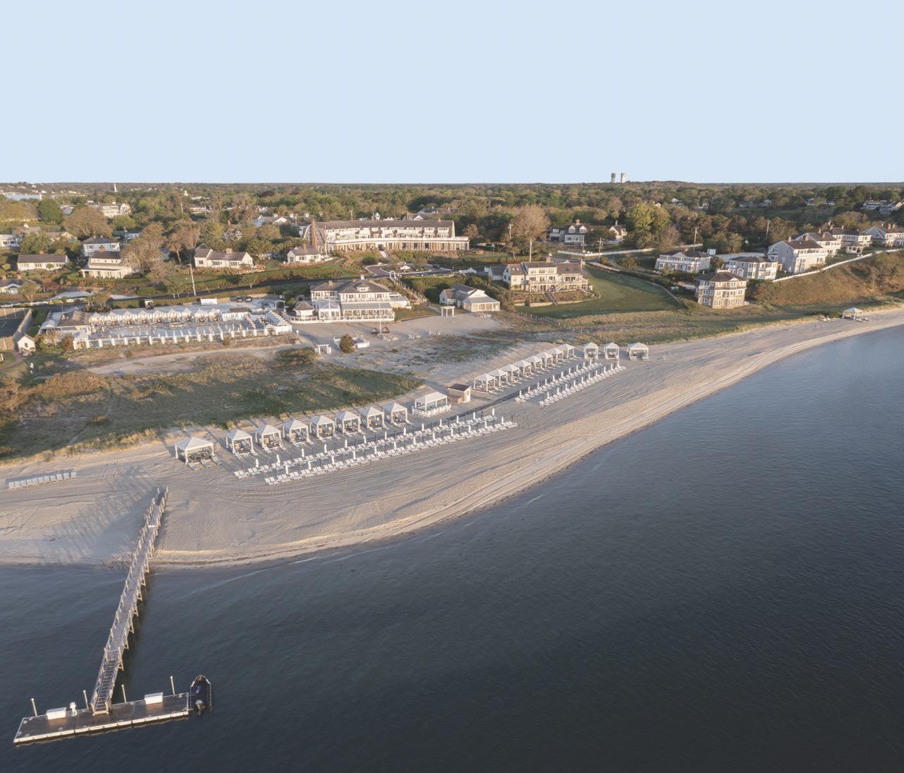 Aerial view of a beachfront with white canopies and a wooden pier.
