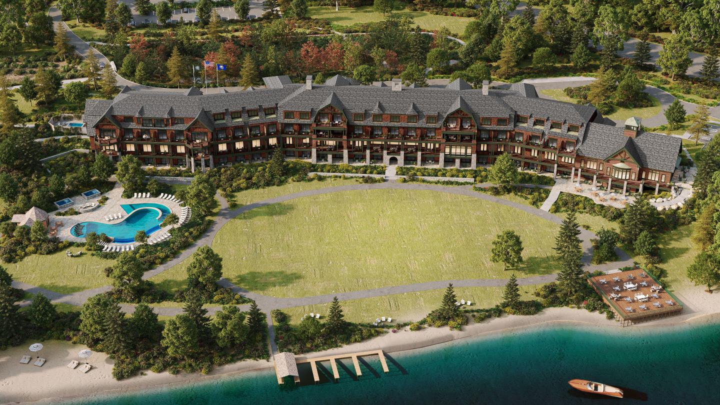 Large resort with pool and green lawn near a lake, surrounded by trees.