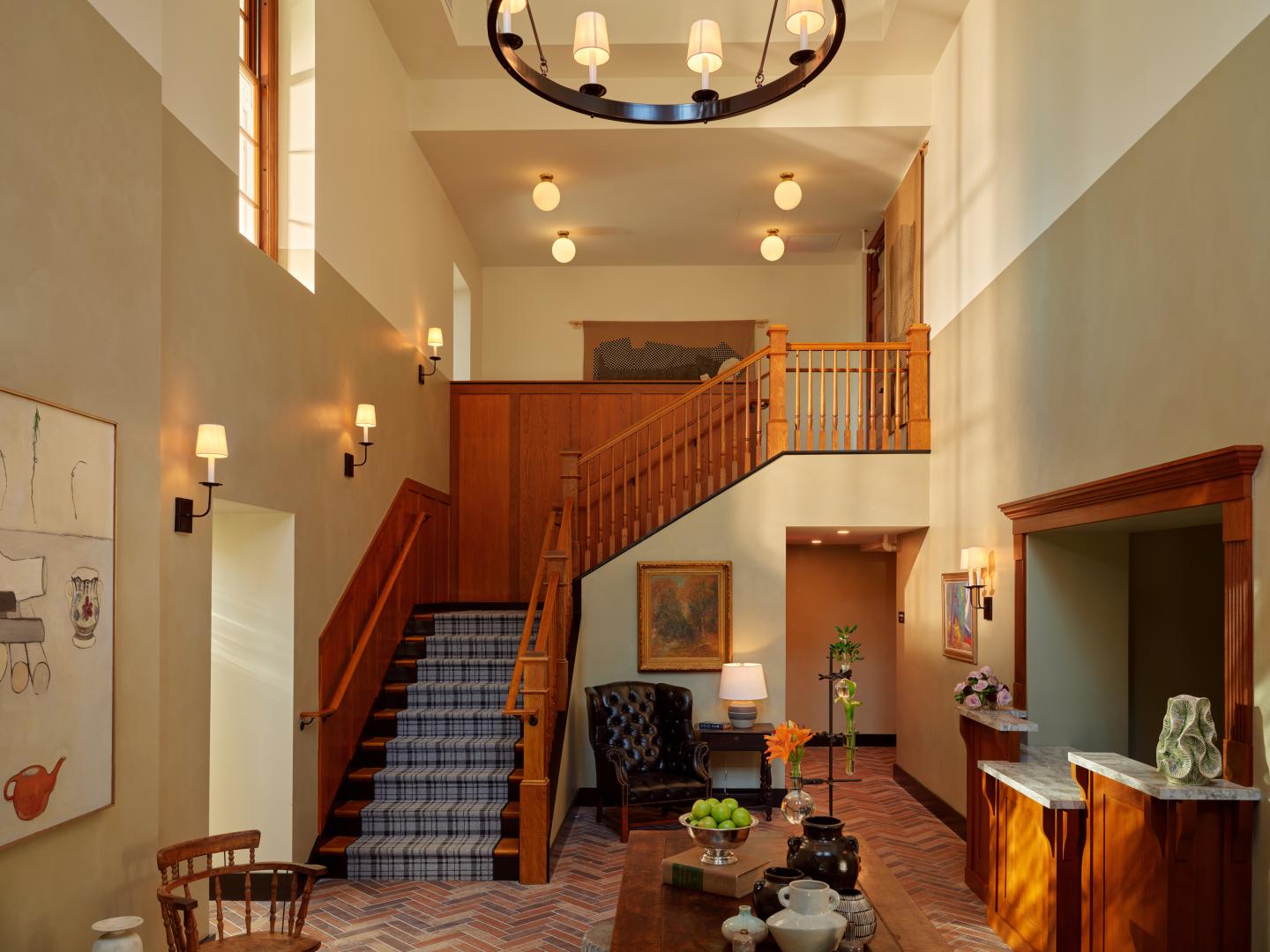 Spacious lobby with staircase, warm lighting, and wooden accents.