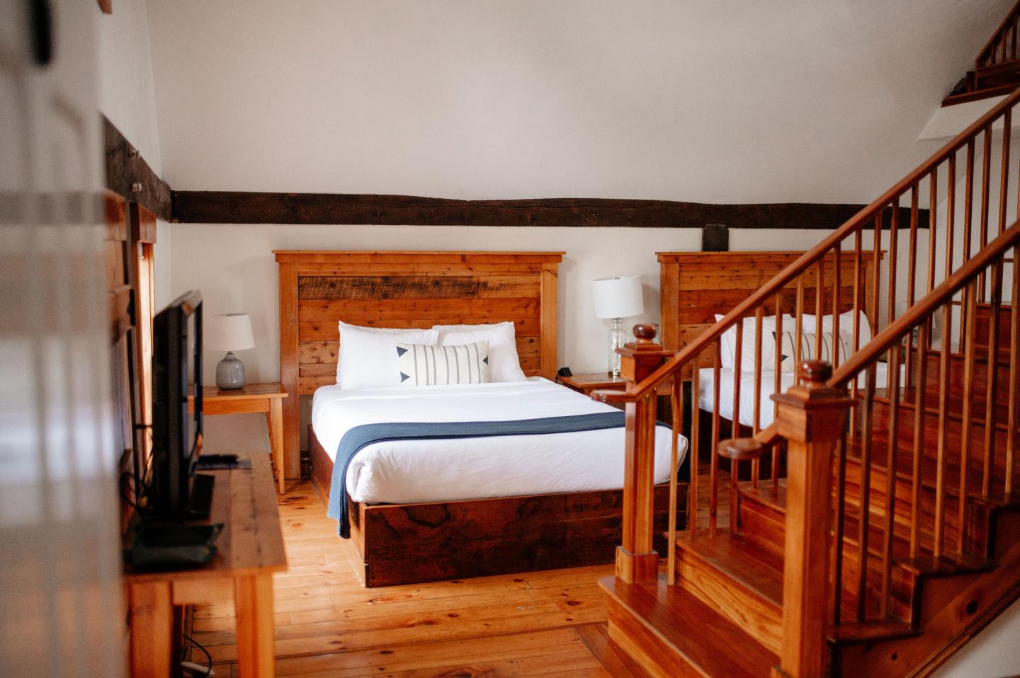 Cozy bedroom with wooden furniture, bed, and a staircase.