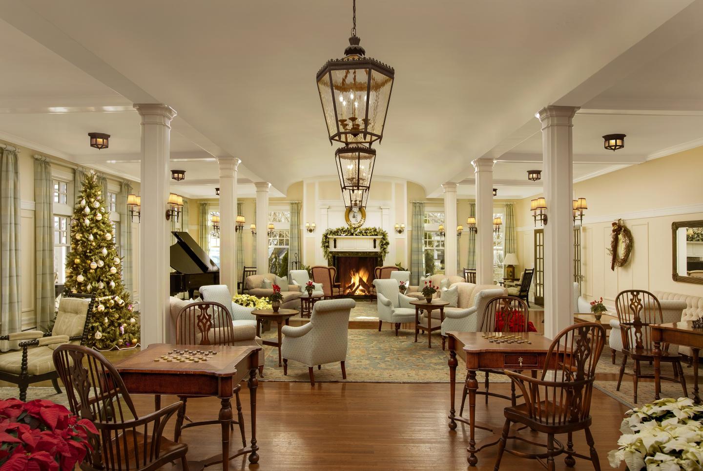 Elegant dining room with Christmas decor, chandeliers, and a fireplace.