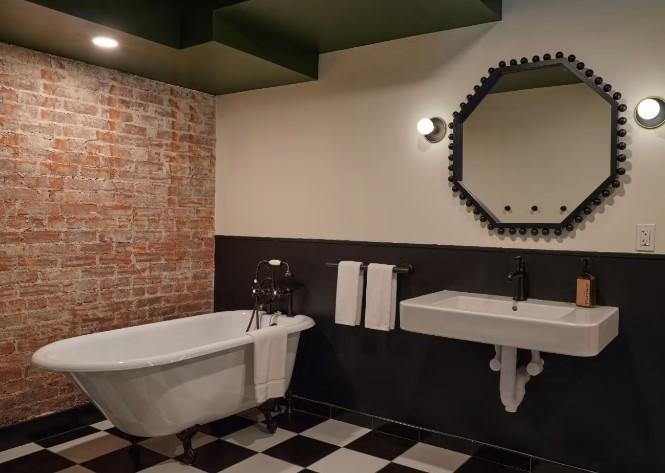 Clawfoot tub, sink, and hexagonal mirror in a modern bathroom.