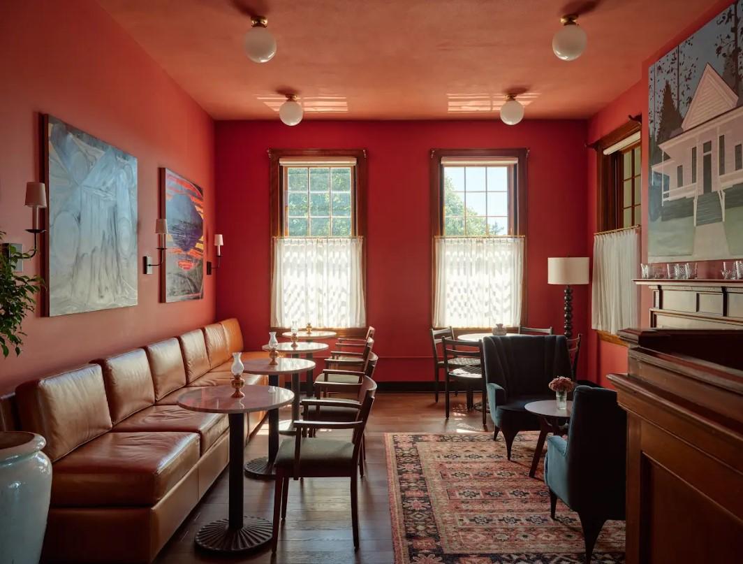 Cozy red-walled cafe with leather seating and large windows.
