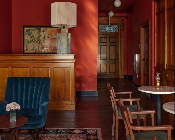 Cozy room with red walls, armchairs, wooden accents, and soft lighting.