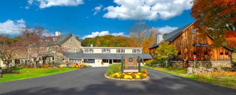 Entrance with autumn trees, buildings, and a welcoming sign.